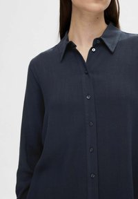 Navy button-up shirt made from a smooth fabric, featuring a pointed collar, long sleeves, and matching buttons along the front.