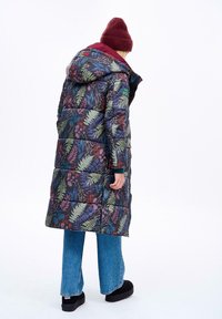 Dlouhá, podšitá parka v tmavě modré barvě s květinovým a kapradinovým potiskem. Má kapuci, zipové zapínání a dekorativní detaily na rukávech.
