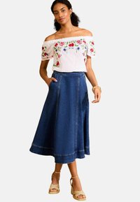 Off-the-shoulder white blouse with floral embroidery paired with a navy denim A-line skirt featuring pockets and a hemmed bottom.