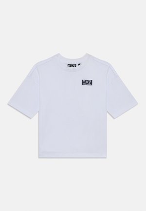 T-shirt bianco in cotone con maniche corte, scollatura rotonda e una piccola toppa con logo nero sul davanti. Vestibilità ampia e texture liscia.