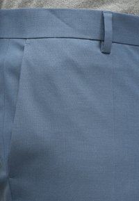 Világoskék nadrág texturált anyagból, egyenes szabású, egyszerű derékpánttal és finom varrási részletekkel.