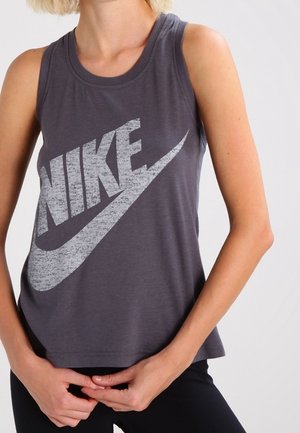 Personne portant un débardeur Nike gris foncé sans manches avec le logo en grand imprimé blanc délavé sur la poitrine.