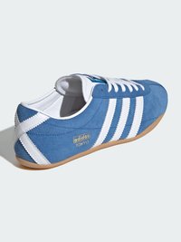 B baskets en cuir suédé bleu avec des rayures blanches, dotées d'une semelle en gomme et de la marque dorée « adidas TOKYO ». Design à lacets avec un bout arrondi.