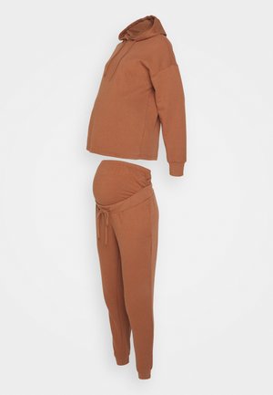 Majica za trudnice i trenirke u boji rđe. Mekani, rastezljivi materijal s opuštenim krojem, s remenom na vezanje i džepovima.