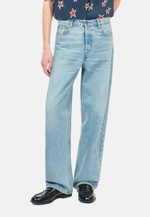 Lichtblauwe wijde jeans van denim, met een klassiek vijf-pocket ontwerp en subtiele vervaging. Gepaard met zwarte leren schoenen.