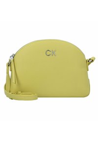 Borsa a tracolla gialla in pelle con parte superiore arrotondata, logo "CK" in argento, chiusura a zip e tracolla rimovibile. Texture liscia con hardware minimale.