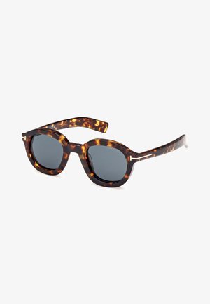 Ochelari de soare în carapace de țestoasă, cu lentile gri, rame geometrice rotunde și accente metalice pe brațe. Designul texturat adaugă interes vizual.