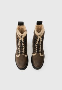 Botas de cuero marrón con forro de piel sintética, cordones negros y una suela de goma resistente. Cuenta con un lazo en el talón para facilitar su uso.