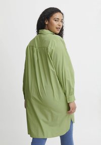Camicia a maniche lunghe verde chiaro con colletto, polsini abbottonati e taglio dritto. Presenta una piega sul retro per un maggior movimento e una vestibilità rilassata.