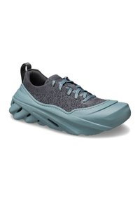 Grauer Sportschuh mit strukturiertem Obermaterial, hellblauen Akzenten, dicker Sohle mit Rillen und einer Zuglasche an der Ferse für ein einfaches Anziehen.