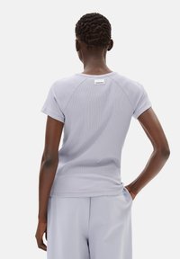 Licht lavendelkleurig geribbeld T-shirt met korte mouwen, ronde halslijn en een klein label aan de achterkant. Gladde textuur en aansluitend ontwerp.