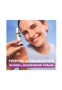 NIVEA Luminous Skin Glow Serum in einer klaren Glasflasche mit einem silbernen Tropferdeckel. Glatte Textur, umgeben von einem hellblauen Hintergrund.