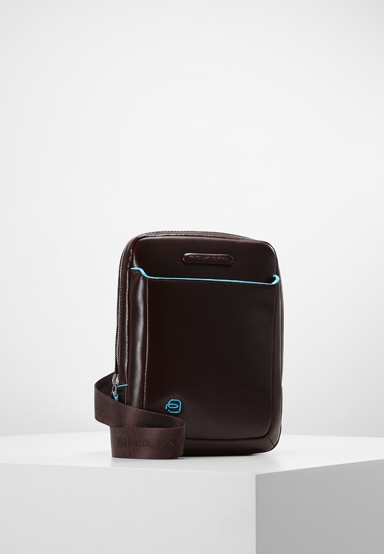 Borsa in pelle marrone di forma rettangolare, con cuciture blu a contrasto, tracolla regolabile e chiusura con zip nella parte superiore.