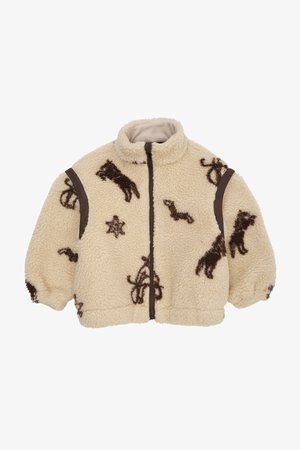 Kreminė fliso striukė su rudais gyvūnų ir žvaigždžių raštais, turi aukštą apykaklę, užtrauktuko uždarymą ir šokolado rudos spalvos akcentines dalis ant pečių.