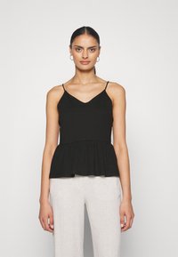 Svart cami-top med tynne stropper, V-hals og et utsvingt peplum-kant. Stoffet ser glatt og lett ut.