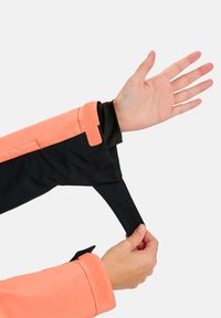 Manșonul jachetei negre și corai cu manșetă reglabilă din Velcro. Țesătura netedă evidențiază culorile contrastante și include o banda de prindere pentru un fit sigur.