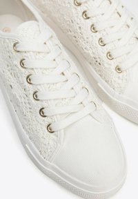 Weiße Sneakers mit einem strukturierten Schnür-Obermaterial, einer glatten Leinenspitze und Metallösen, weißen Schnürsenkeln und einer gemusterten Gummisohle.
