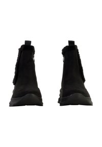 Bottines noires en daim souple avec une doublure duveteuse, dotées d'une semelle lisse et d'une languette pour faciliter l'enfilage.