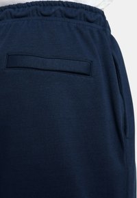 Pantalons de survêtement bleu marine avec une taille élastique, dotés d'une simple poche arrière et d'un tissu doux et texturé.