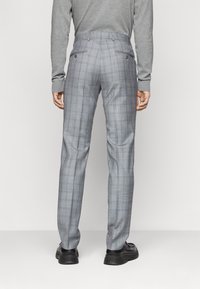 Pantaloni a quadri grigi con una vestibilità sartoriale, tasche posteriori e passanti per la cintura, completati da una texture di tessuto liscia.
