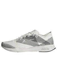 Zapatilla deportiva blanca con un upper de tela ligera que presenta rayas diagonales negras, cordones planos y una suela de goma texturizada.