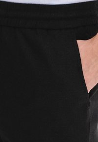 Czarne dresy z bawełny o gładkiej fakturze, z elastycznym paskiem w talii i kieszeniami po bokach. Prosty design z luźnym krojem.