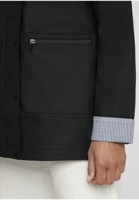 Black waterproof jacket with a horizontal zippered pocket, featuring a striped cuff hem and smooth texture. Visible button closure detail.