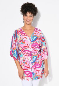 Tunic a stampa floreale colorata in rosa, rosso e turchese. Presenta un collo a V, maniche corte e una coulisse regolabile in vita.