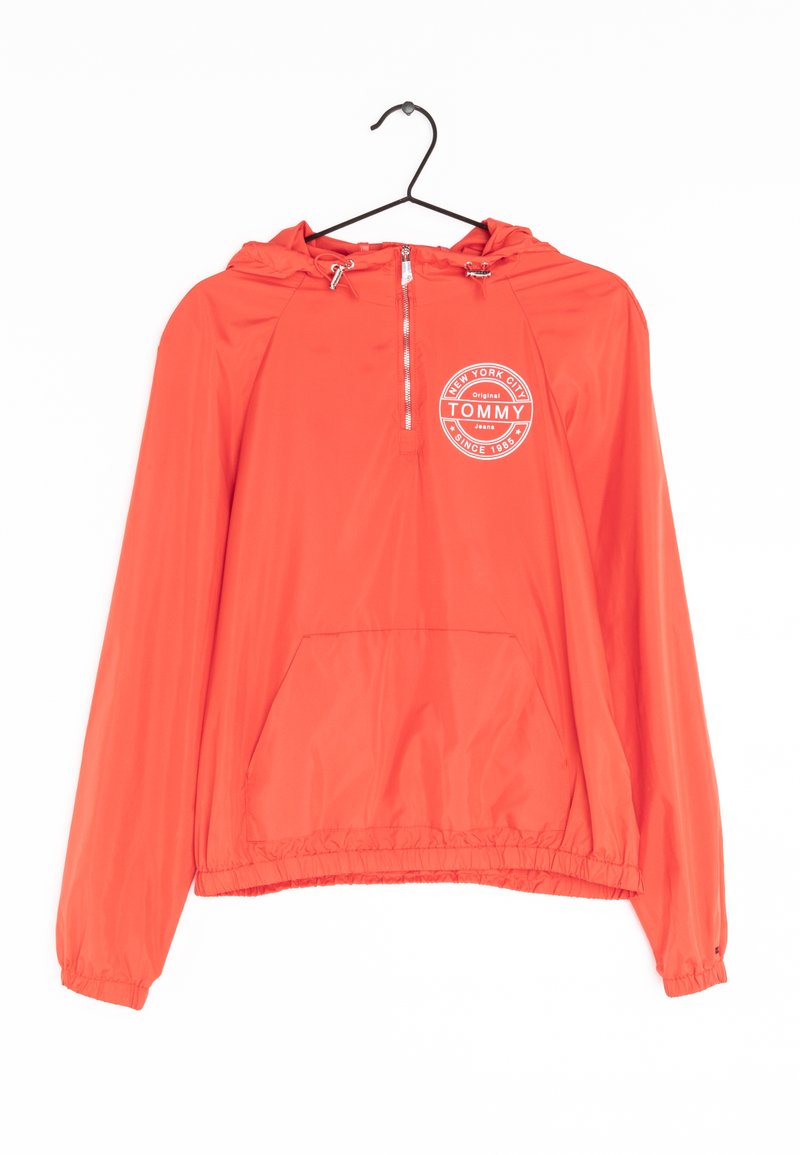 Czerwona bluza z kapturem z zamkiem błyskawicznym z przodu, kieszenią typu kangur na dole, elastycznymi mankietami oraz białym, okrągłym logo "Tommy New York City Since 1985" na klatce piersiowej.