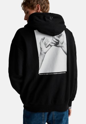 Black hoodie with a large graphic of two hands making a promise on the back. Features a cozy fit and ribbed cuffs, hip-length design.