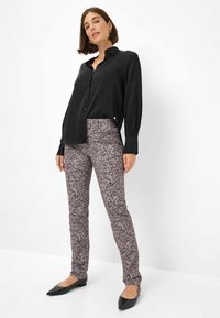 Zwarte lange mouwen overhemd met knopen, gecombineerd met aansluitende grijze broek met luipaardpatroon. Schoenen zijn zwarte ballerina's. Glad stoffen oppervlak.