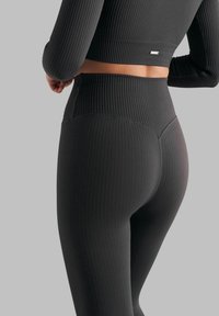 Svarte ribbestrikkede leggings med høy midje, med teksturert overflate og sømdetaljer, designet for en figurnær silhuett.