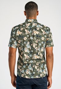 Camicetta a maniche corte in tessuto verde scuro con motivo floreale che presenta fiori beige e blu, colletto a punta e orlo dritto.