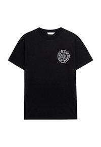 T-shirt en coton noir avec un col rond. Présente un design circulaire imprimé en blanc sur la poitrine gauche avec du texte et des graphiques. Manches courtes.
