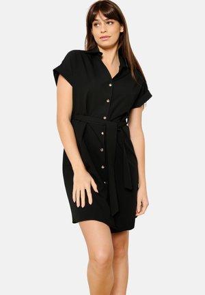 Robe noire à manches courtes, avec une taille ceinturée et des boutons dorés, présentant une texture de tissu lisse et une longueur au genou.