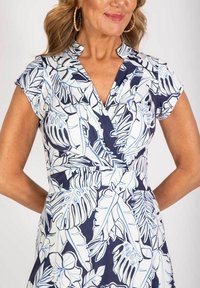 Marineblaues Kleid mit weißem botanischem Muster, kurzen Ärmeln, V-Ausschnitt und taillierter Taille. Glattes Gewebe mit subtiler glänzender Optik und gefalteten Akzenten.