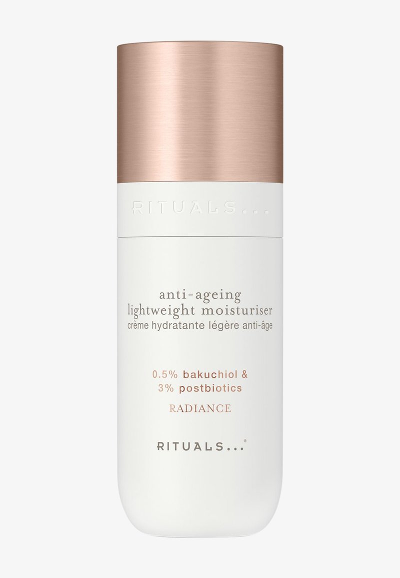 Botella de hidratante ligero anti-edad con tapa de oro rosa, etiquetada con 0,5% bakuchiol, 3% postbióticos, Radiance de Rituals.