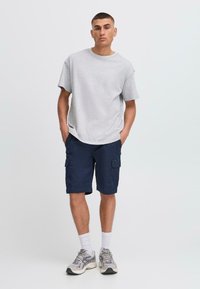 Grå bomull T-skjorte, avslappet passform. Marineblå cargo-bukser med side lommer. Grå sneakers og hvite sokker fullfører antrekket. Enkel, uformell stil.