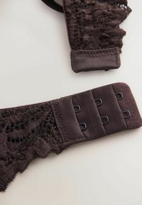 Mørkebrune blonde-BH-kroge med tre rækker og to kolonner af metalbeslag på en neutral baggrund.