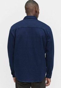 Middengrijze langemouwen shirt gemaakt van gestructureerde stof, met een knoopsluiting kraag en manchet met cuff, met een rechte zoom aan de achterkant.