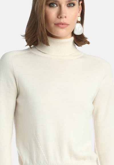 Kremowy sweter z golfem o prążkowanej strukturze i dopasowanym kroju. Charakteryzuje się subtelnym przeszyciem i miękkim, lekkim materiałem.