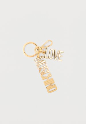 Portachiavi color oro con ciondoli a lettere "LOVE" e "MOSCHINO" e moschettone, su sfondo bianco semplice.