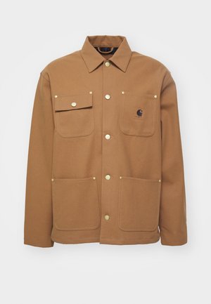 Smeđa jakna od gustog materijala, s ovratnikom, dva prednja džepa s preklopima i gumbima u zlatnoj boji. Uključuje zakrpu s logotipom na prsima.