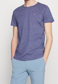 Kurzärmliges, Rundhalsausschnitt-T-Shirt aus meliertem dunkelpurpurfarbenem Stoff mit kleinem Markenlogo auf der Brust. Lässige Passform, leichtes Material.