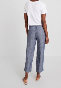 Modré vzorované zkrácené kalhoty s volným střihem, s hladkým materiálem a pasem, doplněné o jednobarevné bílé tričko.