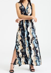 Maxi sukienka z wirującym abstrakcyjnym wzorem w kolorze granatowym, kremowym i jasnoniebieskim. Wykonana z miękkiego materiału, z dekoltem w kształcie litery V i detalem w postaci bocznego rozcięcia.