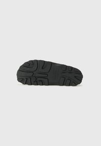 Suola di scarpa in gomma nera con un motivo di battistrada testurizzato per una migliore aderenza, caratterizzata da un logo impresso e un design durevole e robusto.