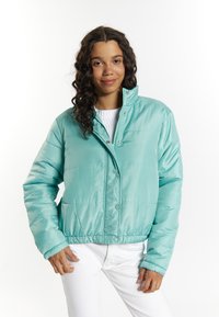 Giubbotto puffer in teal chiaro con chiusura a zip e bottoni, polsini a coste e design leggermente cropped. Materiale liscio e lucido con sezioni cucite.