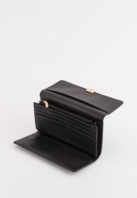 Czarny portfel ze skóry o gładkiej fakturze, wyposażony w złotą sprzączkę, liczne przegródki na karty oraz zamykaną na zamek kieszonkę na monety. Widok z otwartej strony.