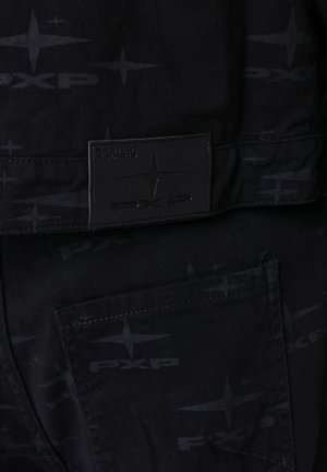 Schwarze Canvas-Hose mit einem Ton-in-Ton-Logo-Muster und einem rechteckigen Markenlabel, das am Bund aufgenäht ist, mit einer sichtbaren Gesäßtasche.